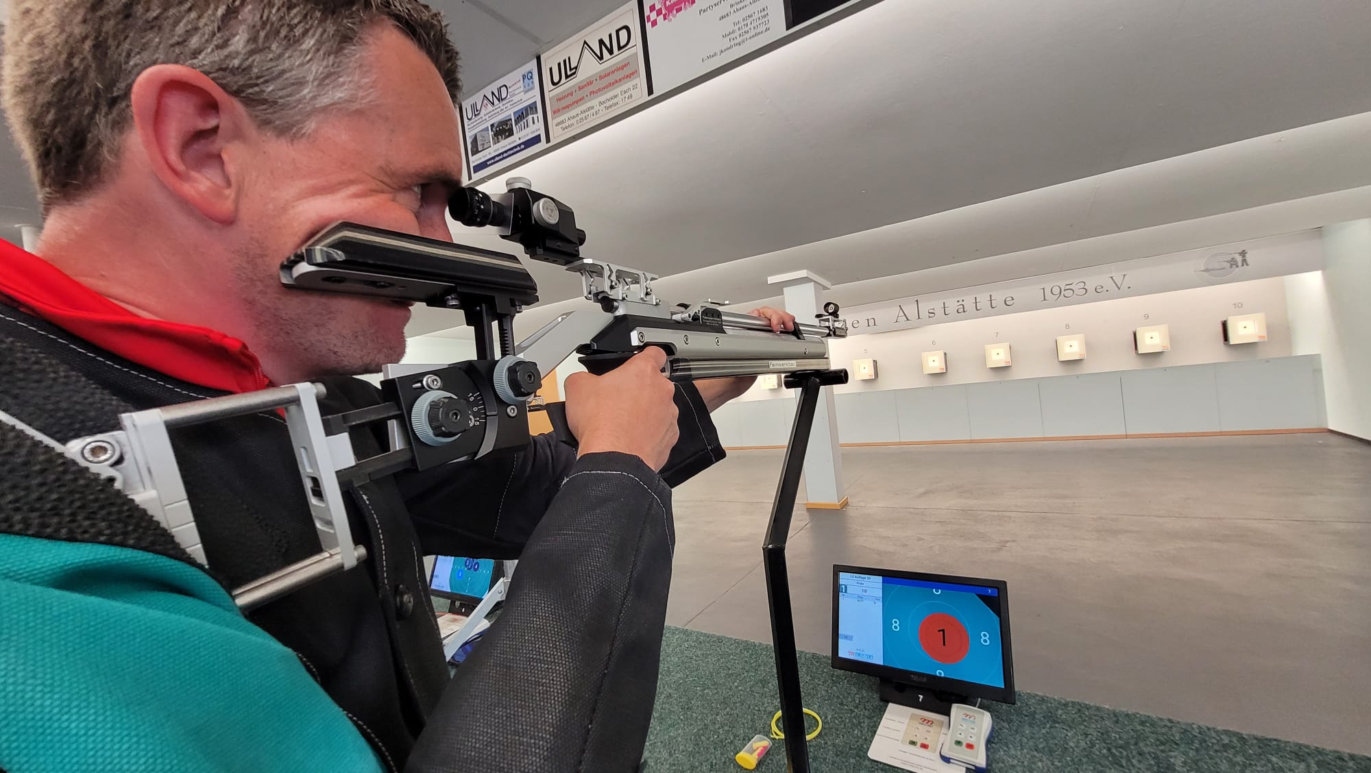 Mann zielt mit Gewähr auf eine Zielscheibe.